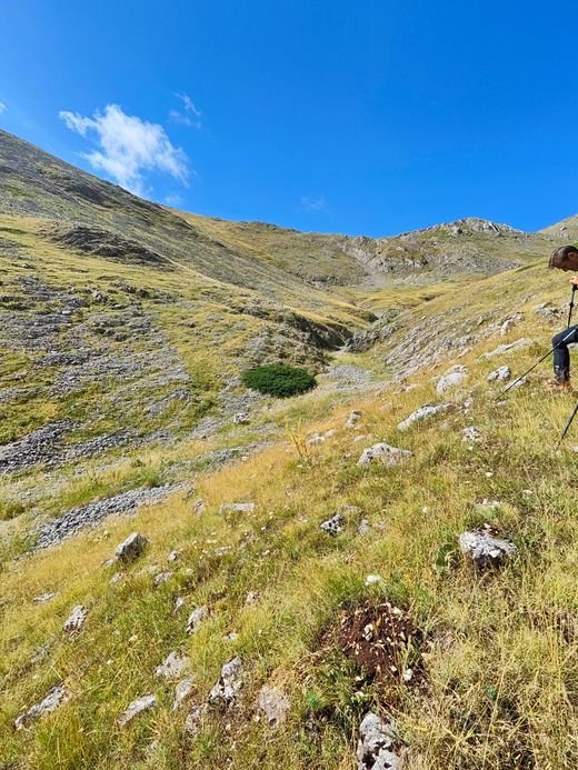 Un anfiteatro di pendii di erba e roccia nel vallone di Ciaccariello, con un escursionista sulla destra