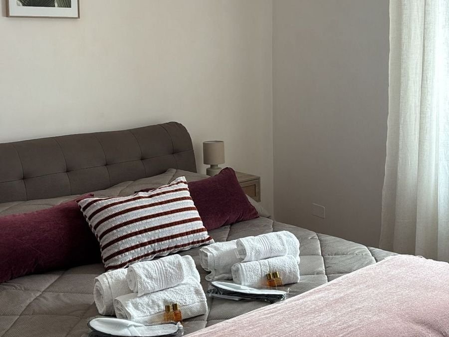Double bedroom with striped cushions and folded towels on the bed