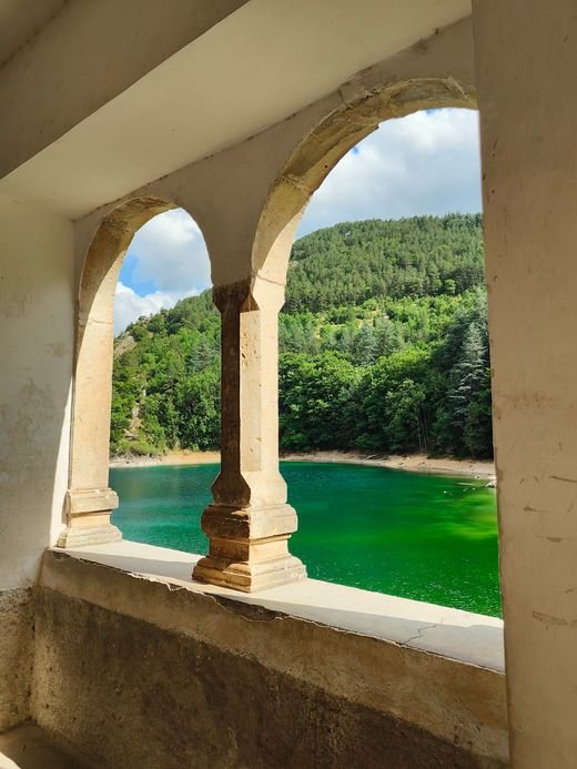 Il lago verde e il bosco visti da una finestra a due archi dell'Eremo di San Domenico