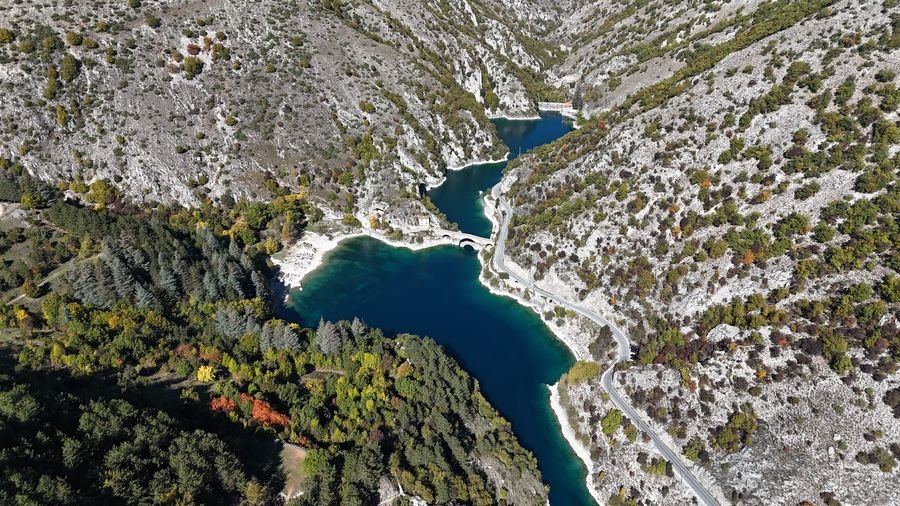 Lake San Domenico from a drone, between pale rock walls, with the bridge and the hermitage on the shore