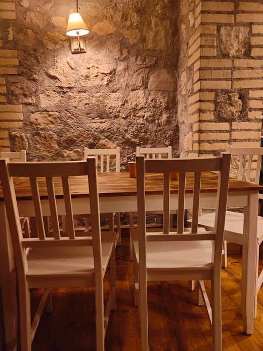 La sala da pranzo del rifugio: tavoli di legno con sedie bianche, un muro di pietra illuminato da una lampada
