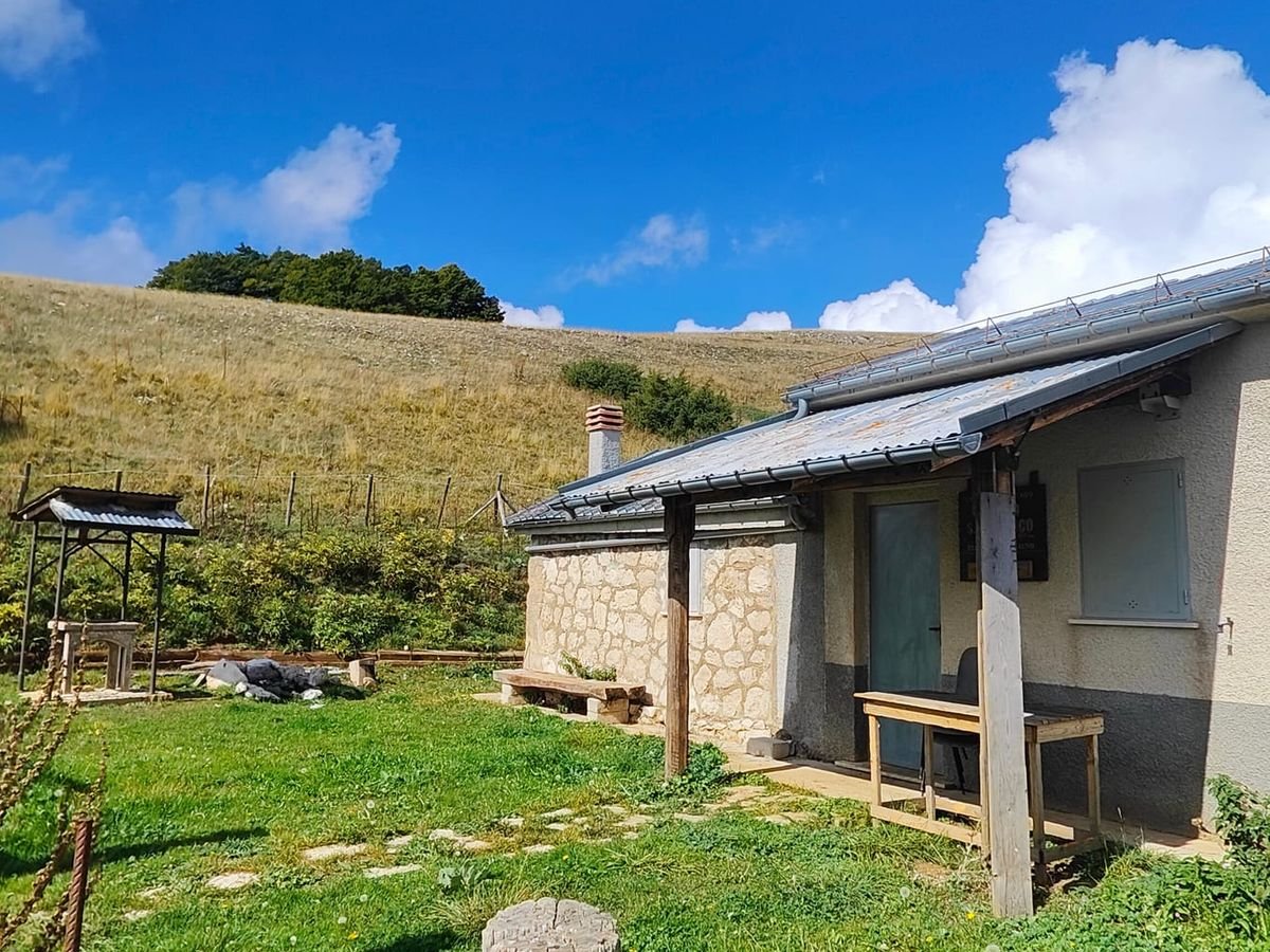 Lo Stazzo Cese Vecchie, una casetta di pietra con il tetto scuro, in un prato sotto i Monti Preziosi