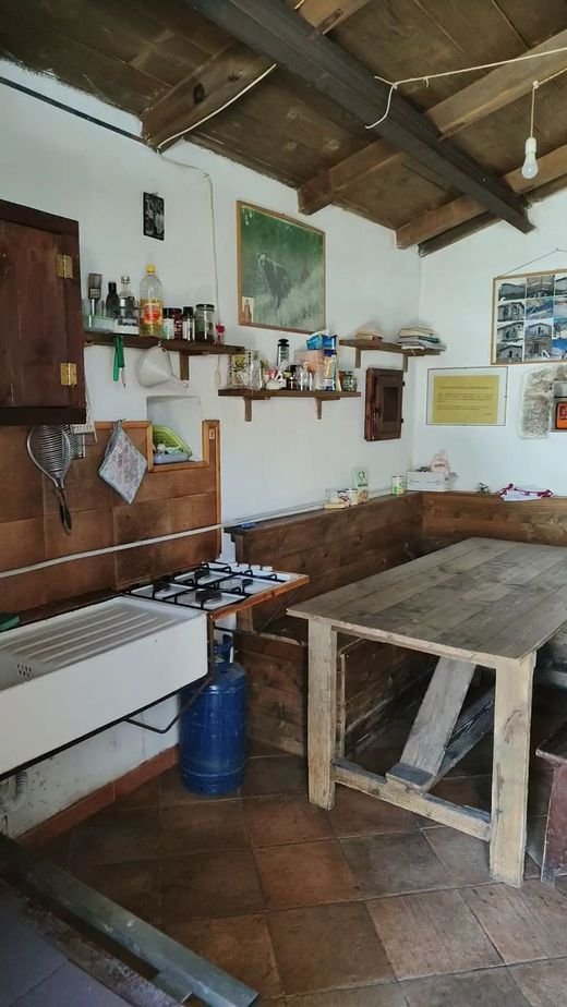 L'interno dello stazzo: un tavolo di legno, le panche, i fornelli a gas e le mensole con barattoli e cartine appese al muro