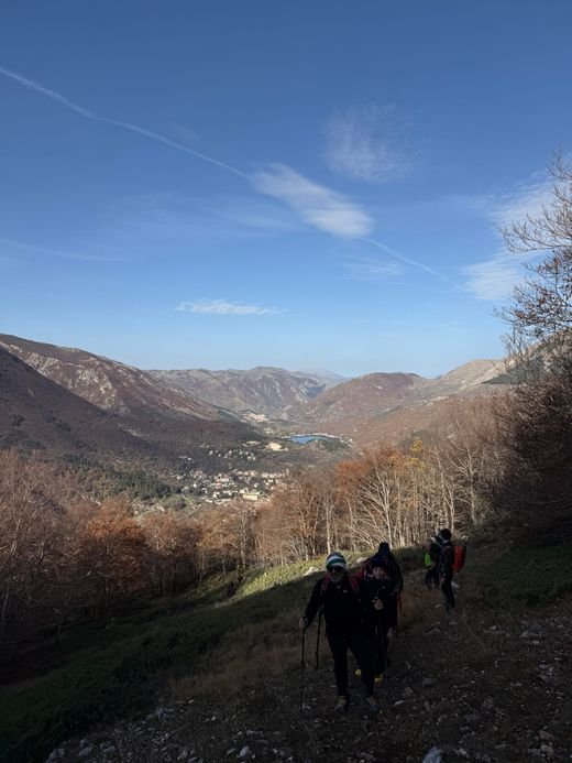 Un gruppo di escursionisti sale sul sentiero 44 in autunno; sotto si vedono Scanno e il lago tra le montagne